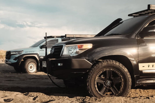 Two off-road vehicles equipped with rugged tires and mags on sandy terrain during an overlanding trip